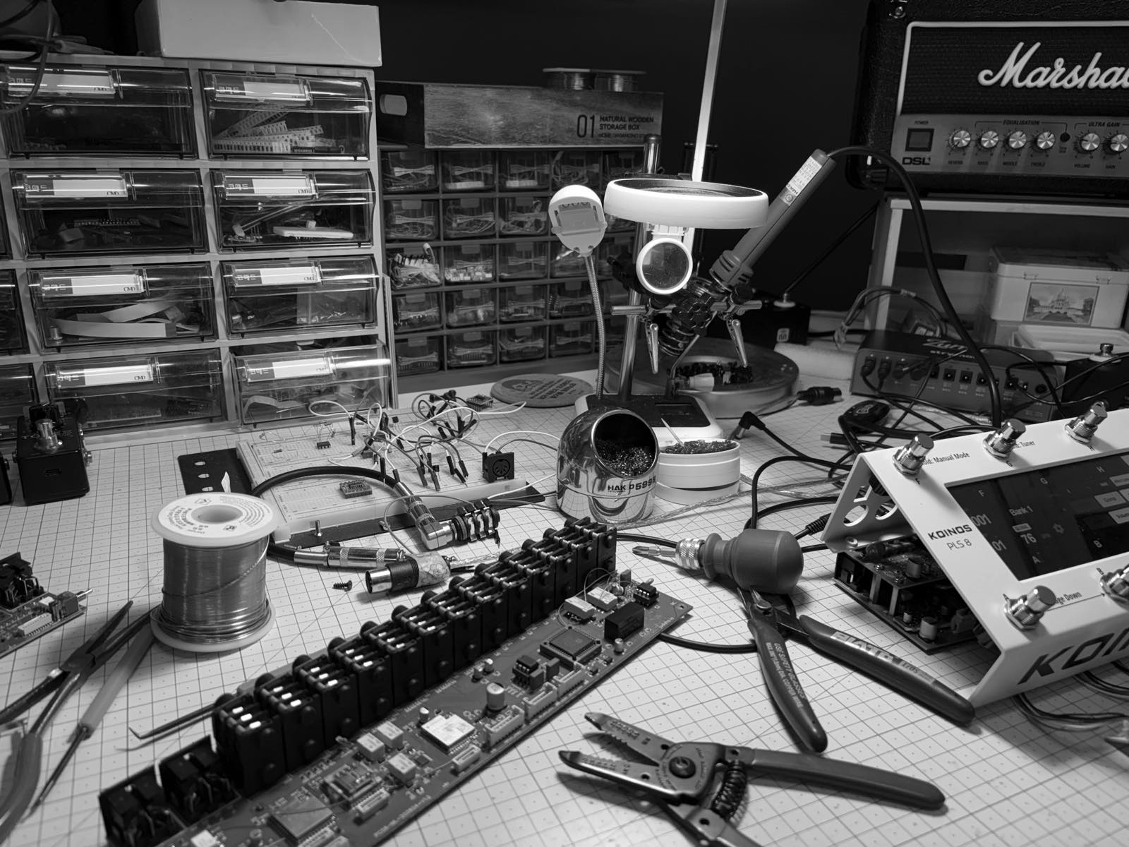 The Judahs workbench: a control board under assembly, a soldering station and a Koinos PLS 8 with its display on